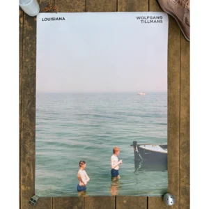 Exhibition poster for Wolfgang Tillmans at Louisiana Museum featuring two young men standing in tranquil turquoise sea water near a boat with vast pale sky above.