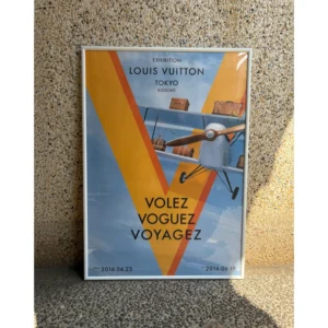 Official Louis Vuitton Volez Voguez Voyagez Tokyo exhibition poster featuring vintage airplane and trunks in iconic orange V design, framed in a white slim aluminum frame, measuring 84x59.5cm.