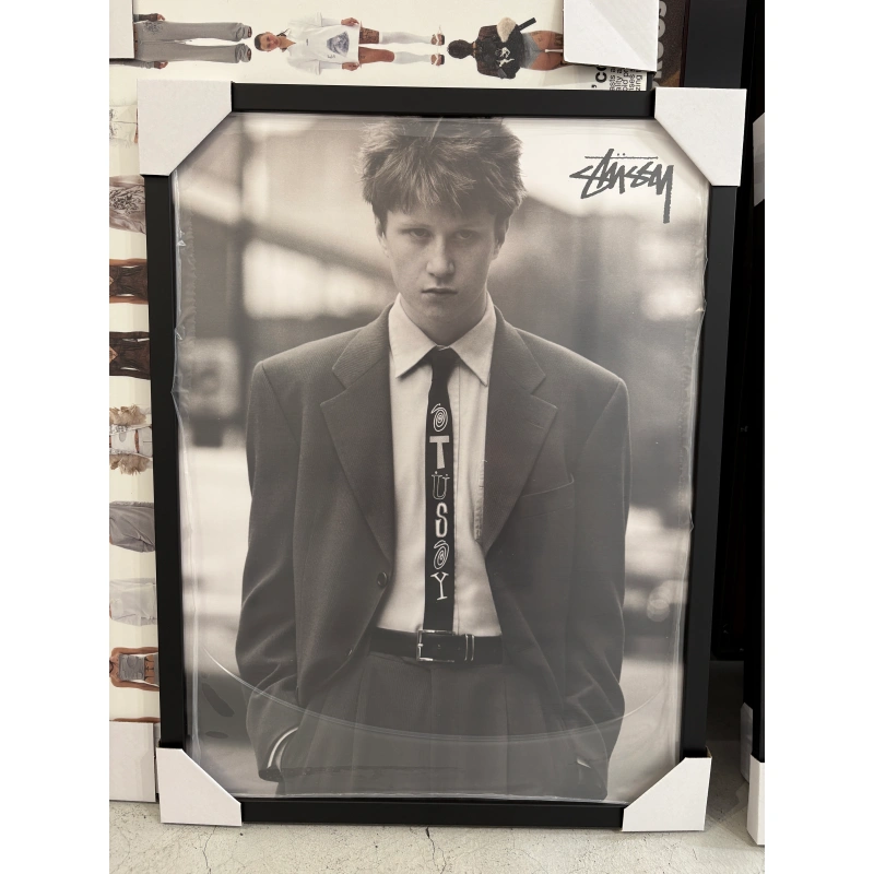 stussy spring19 tie Alt Text: Official Stussy Spring 2019 campaign poster featuring a black and white portrait of a young man wearing an oversized suit with a printed Stussy graphic tie, framed in a black aluminum frame, measuring 59.5x42cm.