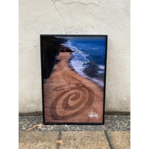 Official Stussy Summer 2020 campaign poster featuring a massive Curly S logo drawn in the beach sand by land artist Jim Denevan, framed in a black aluminum frame, measuring 42x30cm.