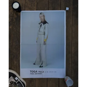 Official double-sided TOGA A/W 2019-20 fashion poster, featuring a collage portrait of a woman in a black jacket over graphic background on Side A (TOGA PULLA), and a medium close-up portrait of a man in a tailored suit and hat framed like film film-strip on Side B (TOGA VIRILIS), measuring 80.5x53cm.