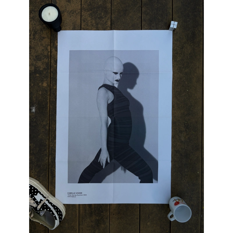toga ss2023 3 1 Official double-sided TOGA S/S 2023 fashion poster shot by Camille Vivier, featuring black-and-white high-fashion portraits of a bald model in avant-garde poses and striped bodywear, measuring 80.5x53cm.