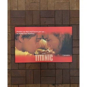 Official vintage 1997 Titanic movie poster featuring Leonardo DiCaprio and Kate Winslet in emotional close-up with iconic quotes on red backdrop, framed in a black wooden frame, measuring 88x55cm.