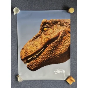 Official Stüssy Fall 2019 campaign poster featuring a close-up profile portrait of a Tyrannosaurus Rex head against a slate grey background with the signature white Stüssy stock logo at the bottom right, measuring 74.5x99cm.